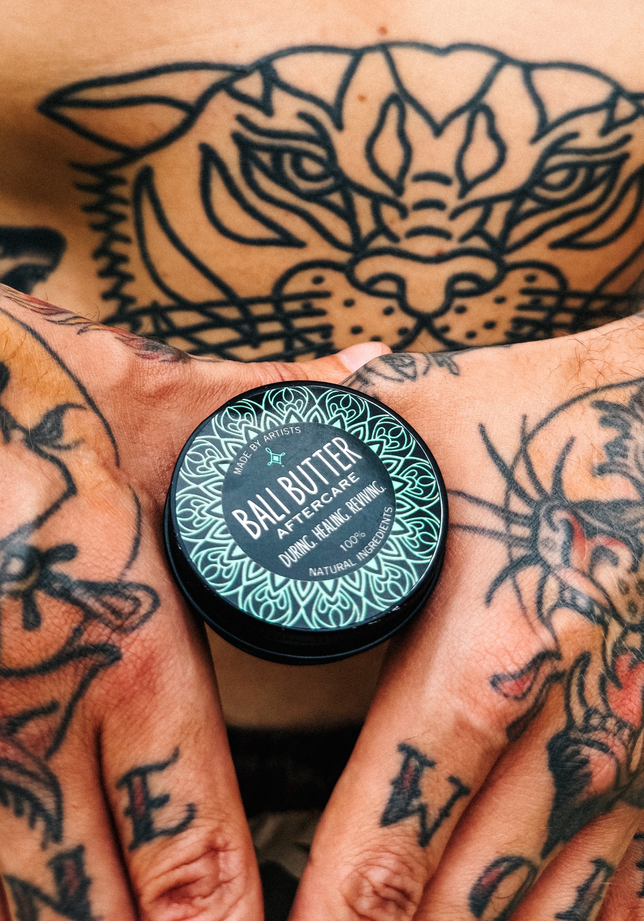 Bali Butter aftercare tin surrounded by tattooed hands