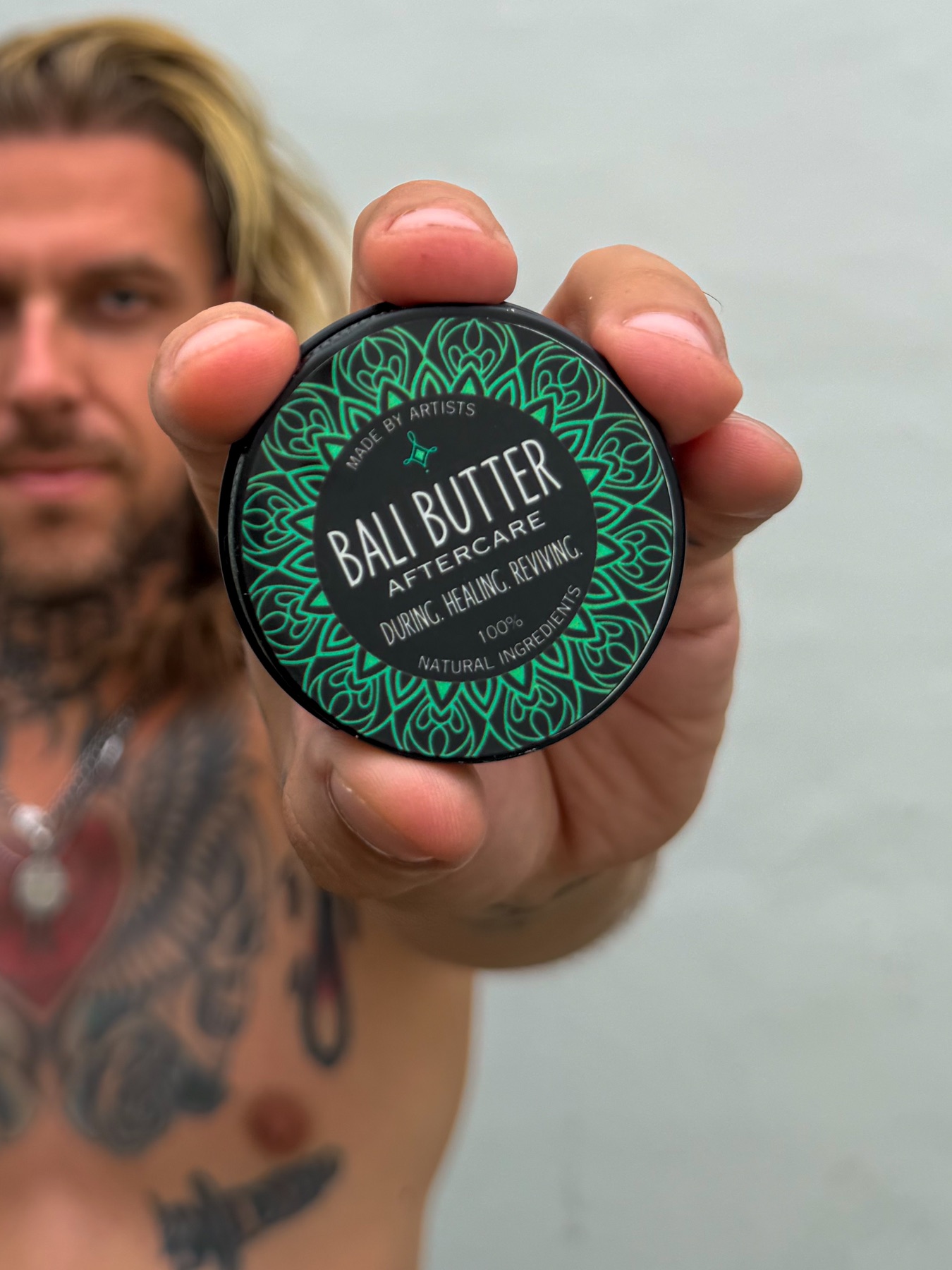 Tattoo artist holding a Bali Butter aftercare tin