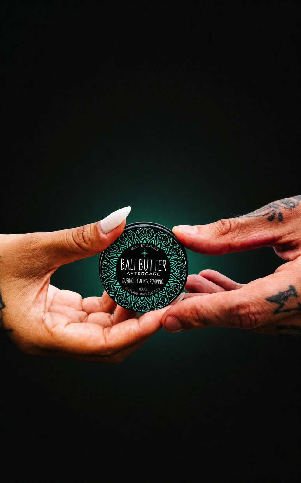 Tattooed hands presenting a Bali Butter tattoo aftercare tin