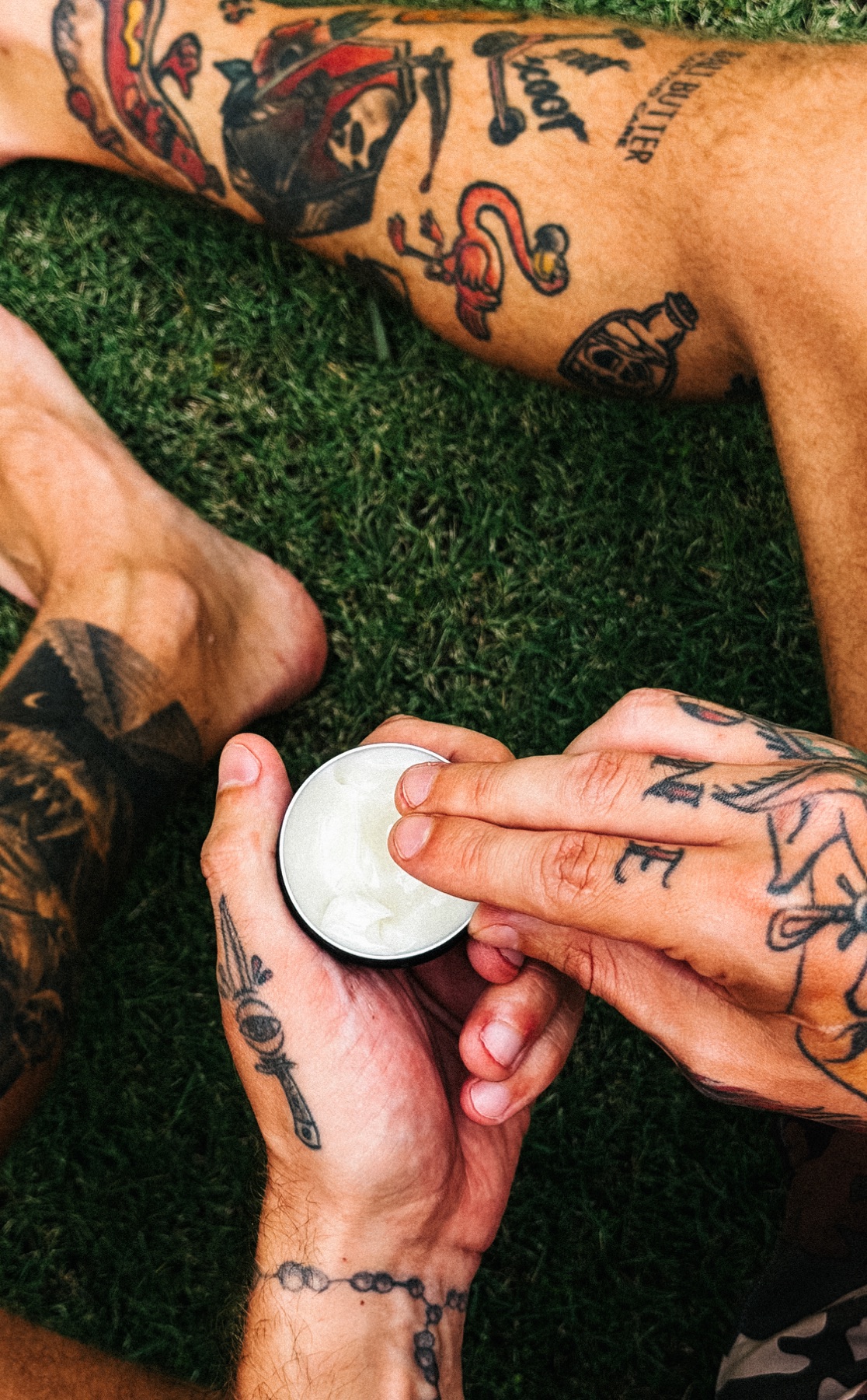 Tattooed hands taking a small amount of Bali Butter from an open tin